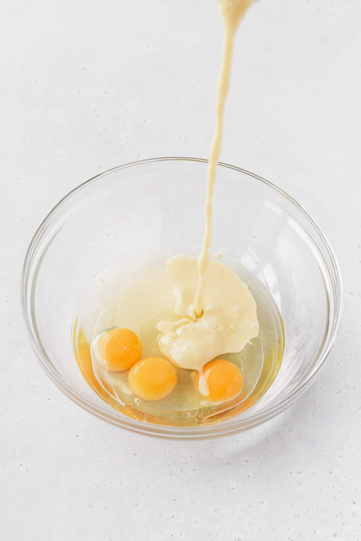 Corn and milk mixture being poured into eggs and oil.