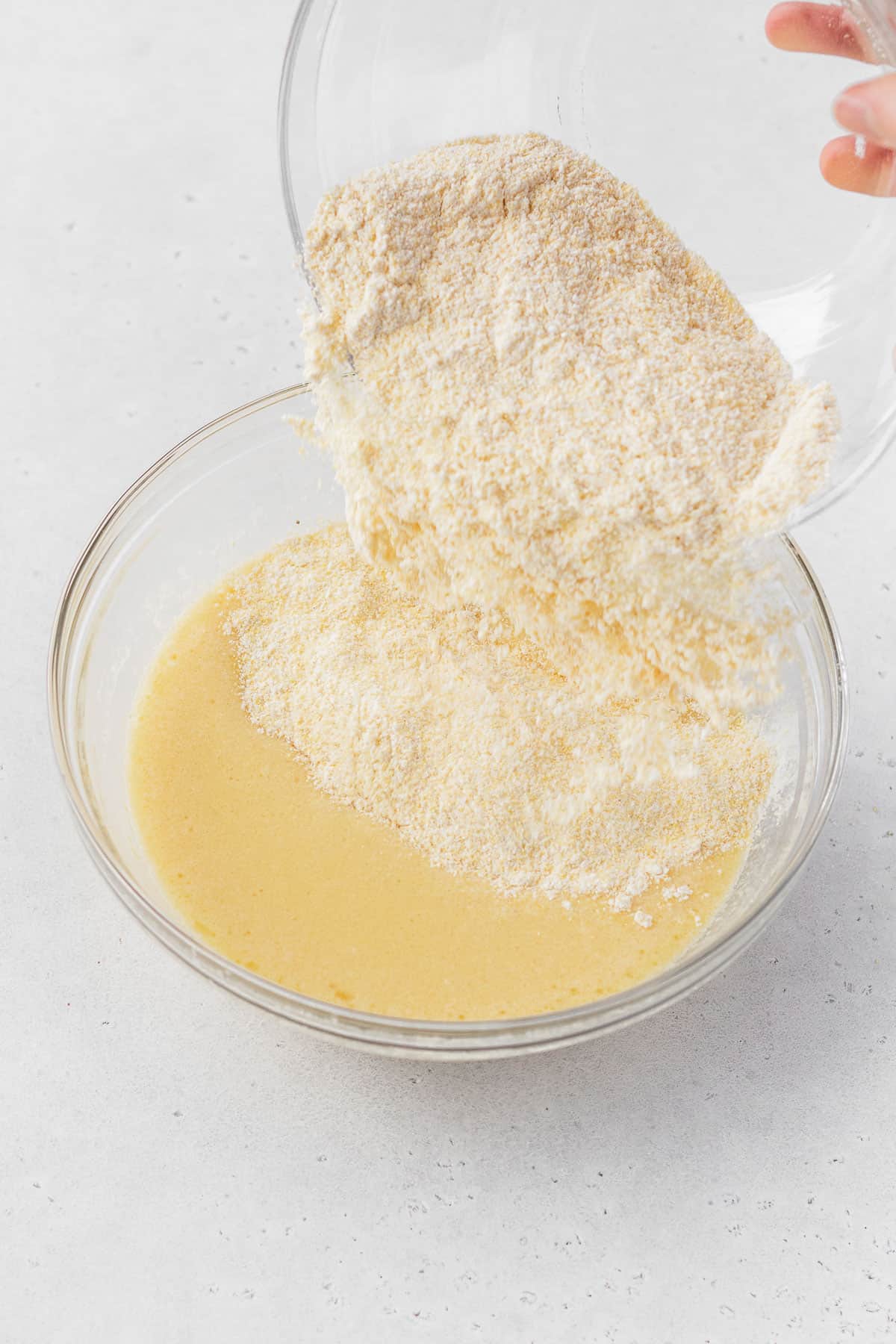 Pouring dry ingredients into bowl with wet ingredients.