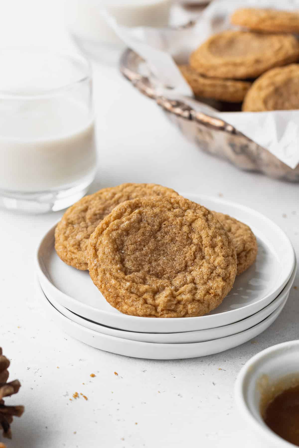 Three gluten free ginger cookies on a stack of white plates.