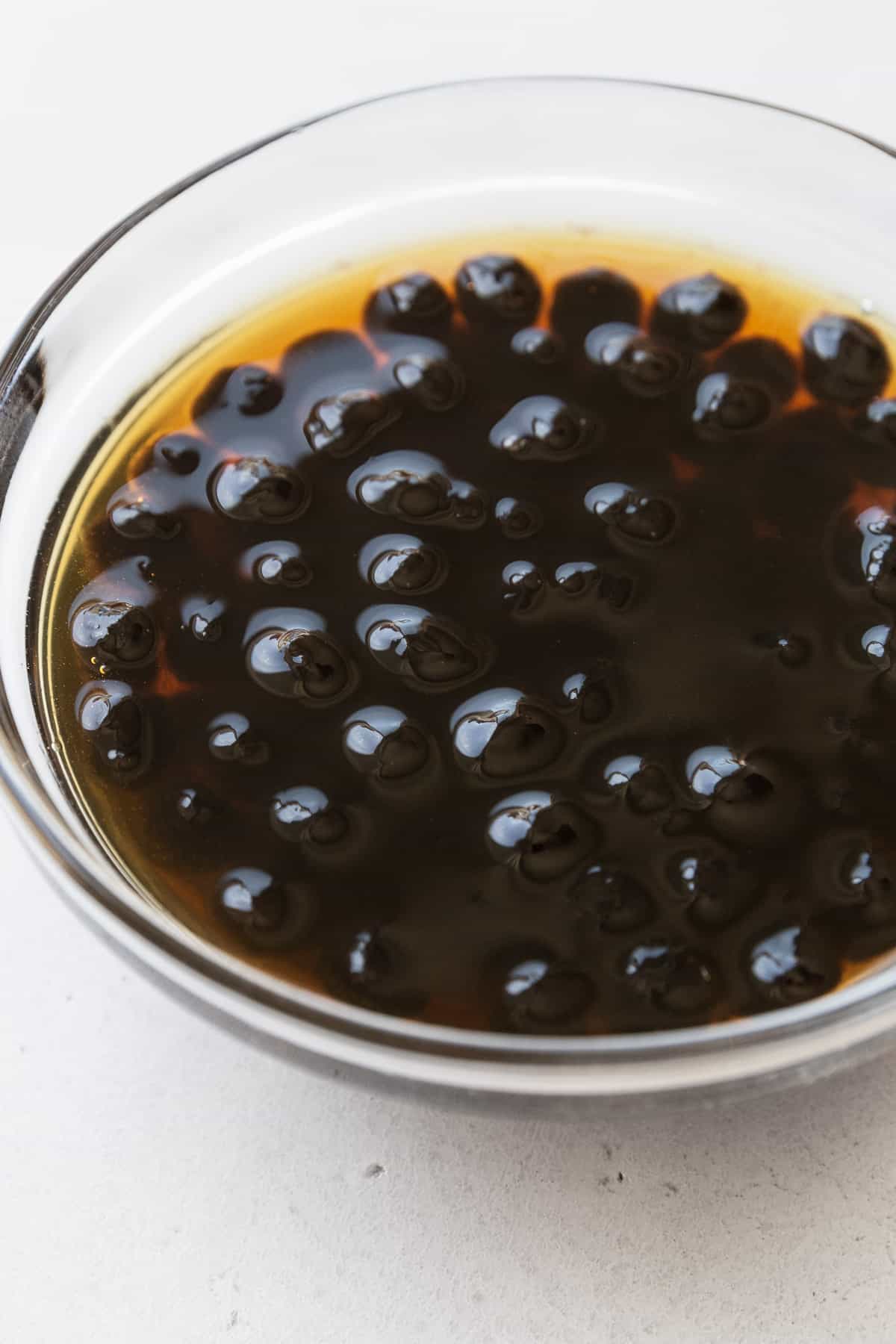 Soaking boba pearls in a small bowl of brown sugar simple syrup.