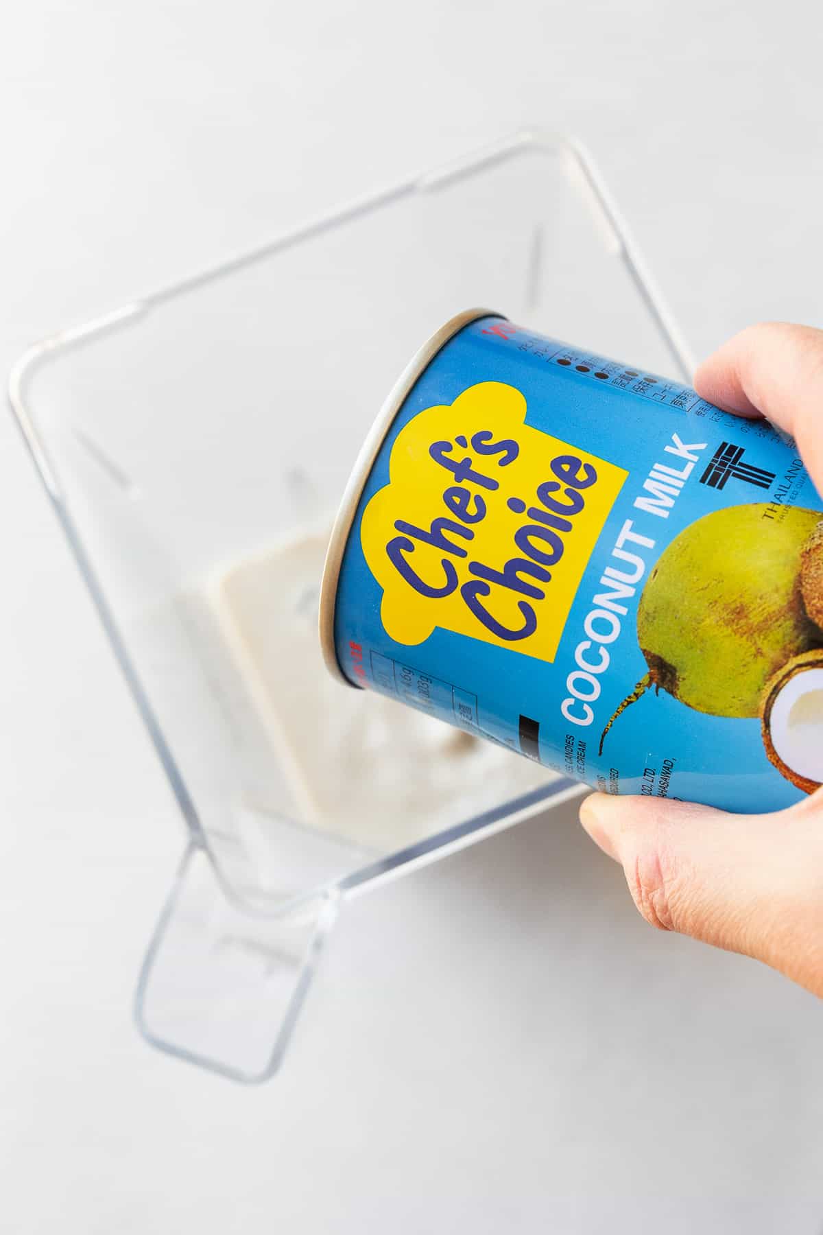 Adding Chef's choice coconut milk to a blender.