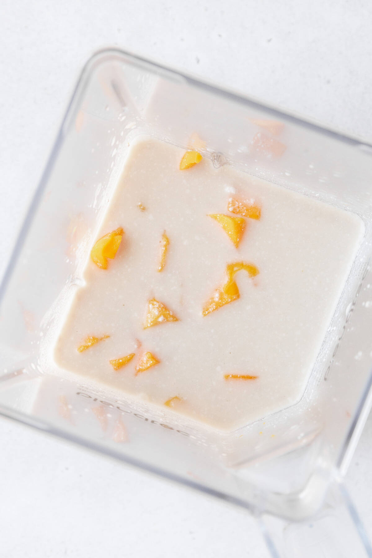 Cubed mango, tea, and coconut milk in a blender.