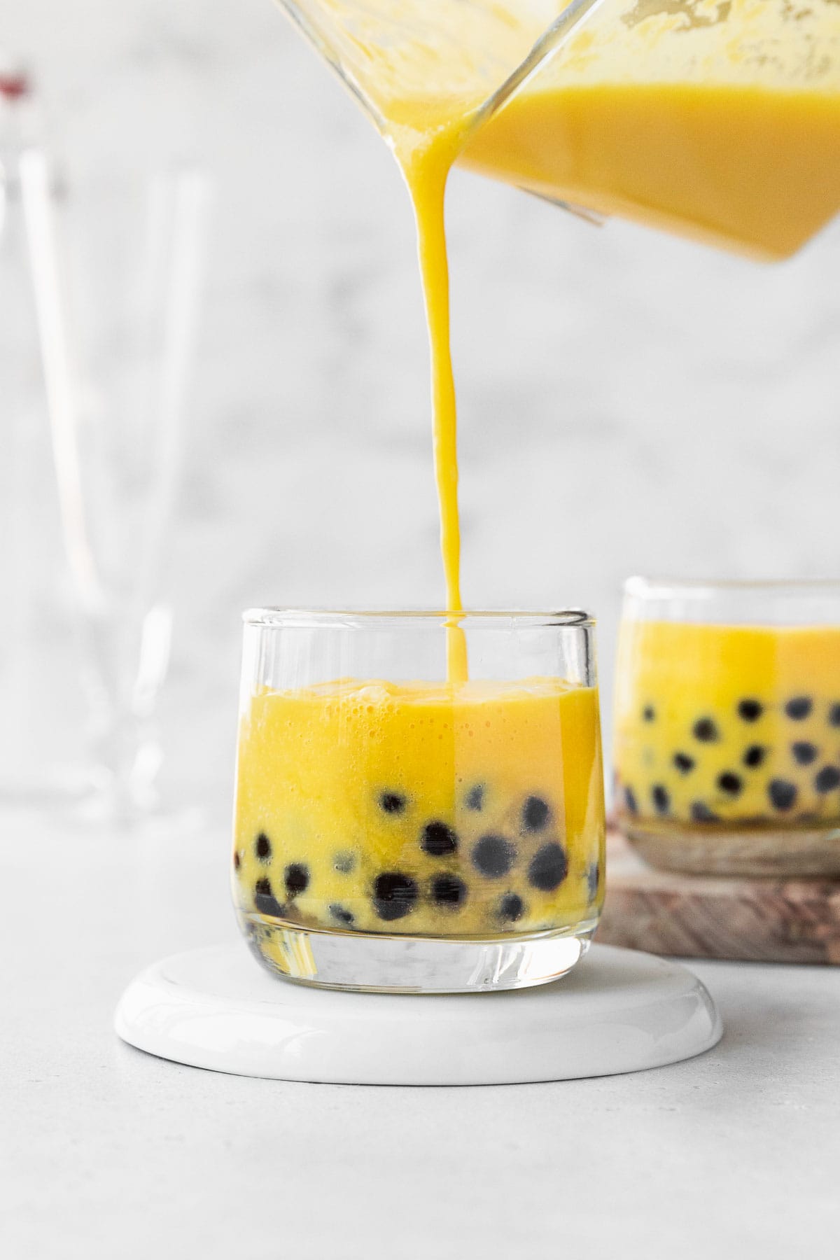 Filling up a small glass with mango boba tea.