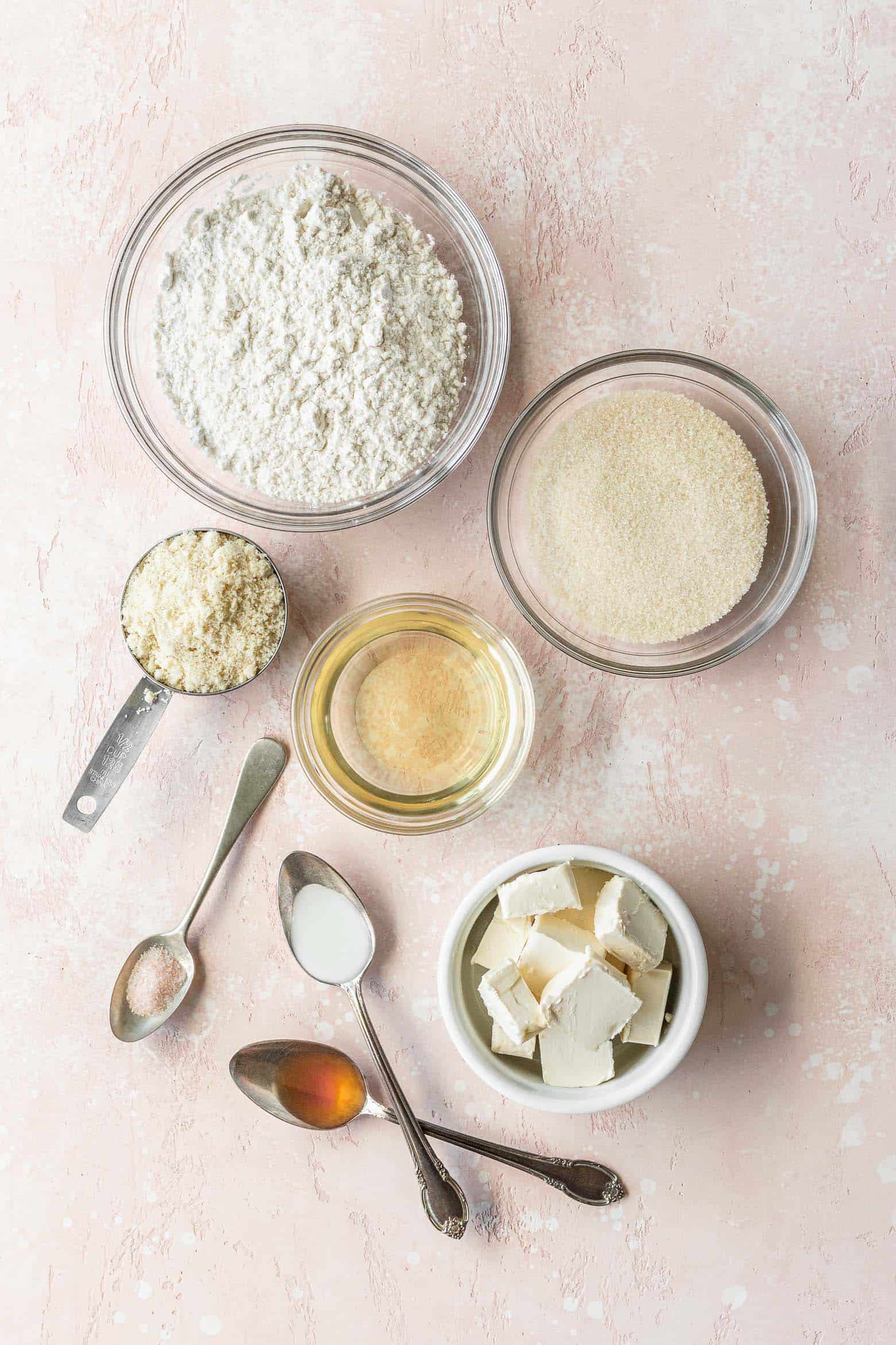 Vegan sugar cookie ingredients measured out into bowls on a pink surface.