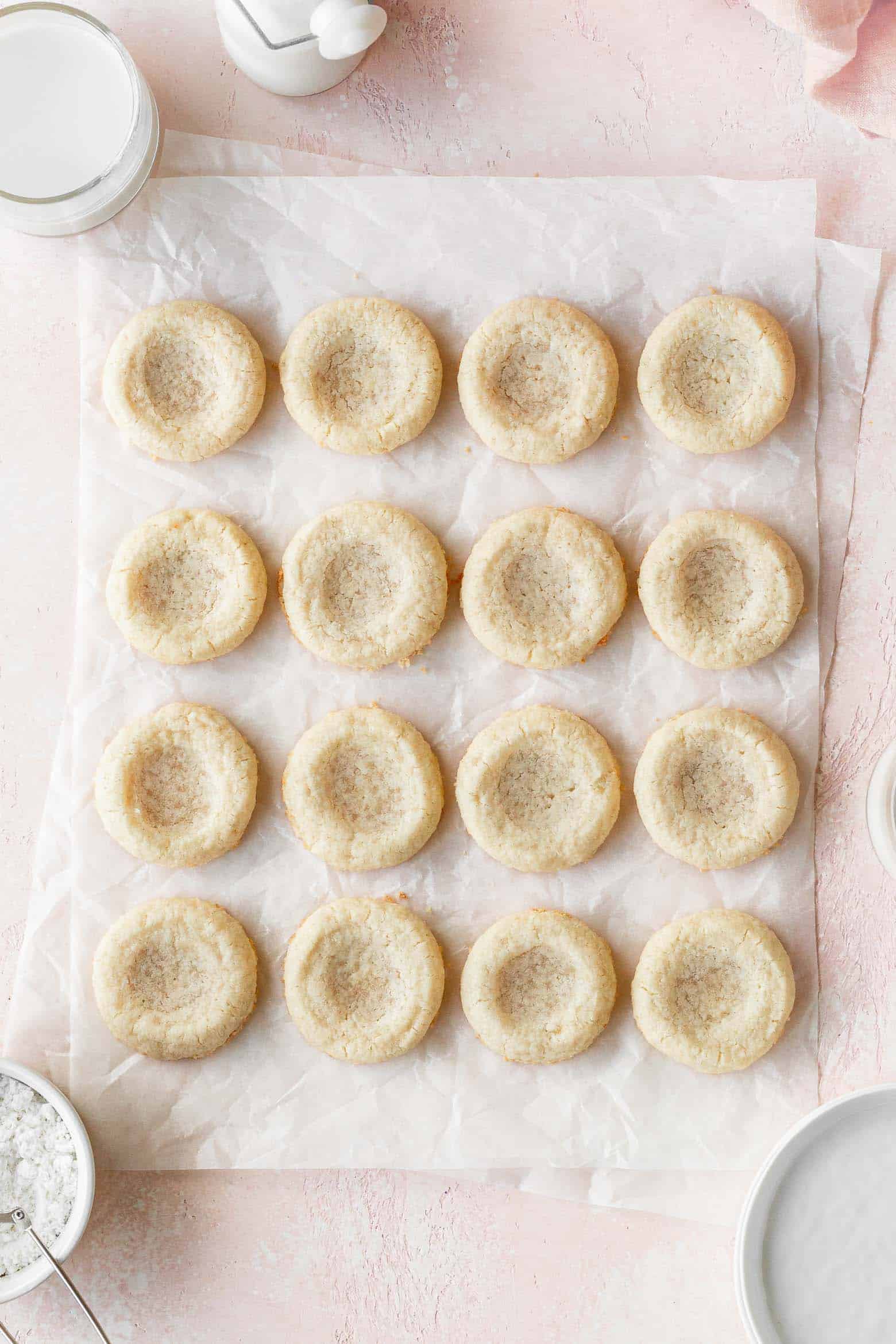 Sugar cookies with indentations on a piece of parchment paper.
