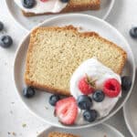 A slice of gluten-free pound cake on a plate with whipped cream and berries.