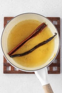 Syrup heated in a pot with a vanilla bean and cinnamon stick.