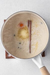 Milk, butter, cinnamon, and an orange peel added to the pot of cooked rice.