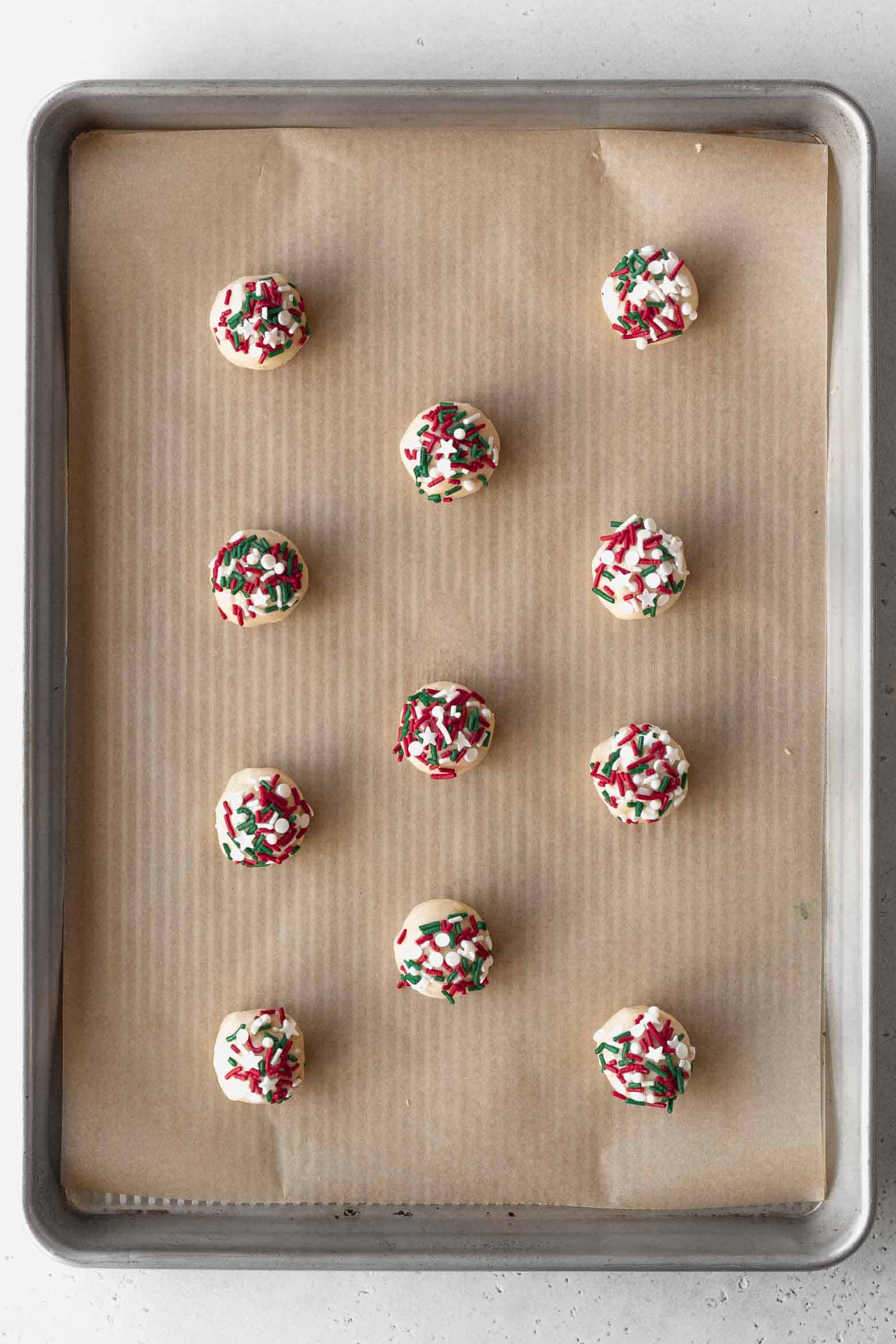 Put sprinkles on balls of cookie dough and place them on a baking sheet.