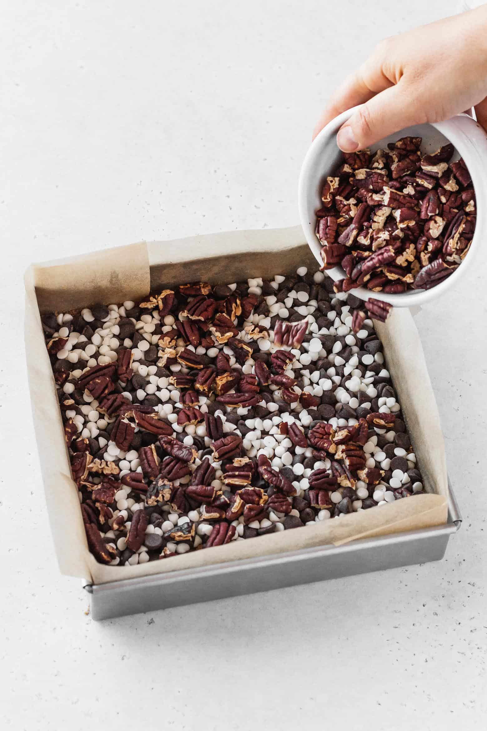 Adding a layer of chopped pecans over a layer of chocolate chips.