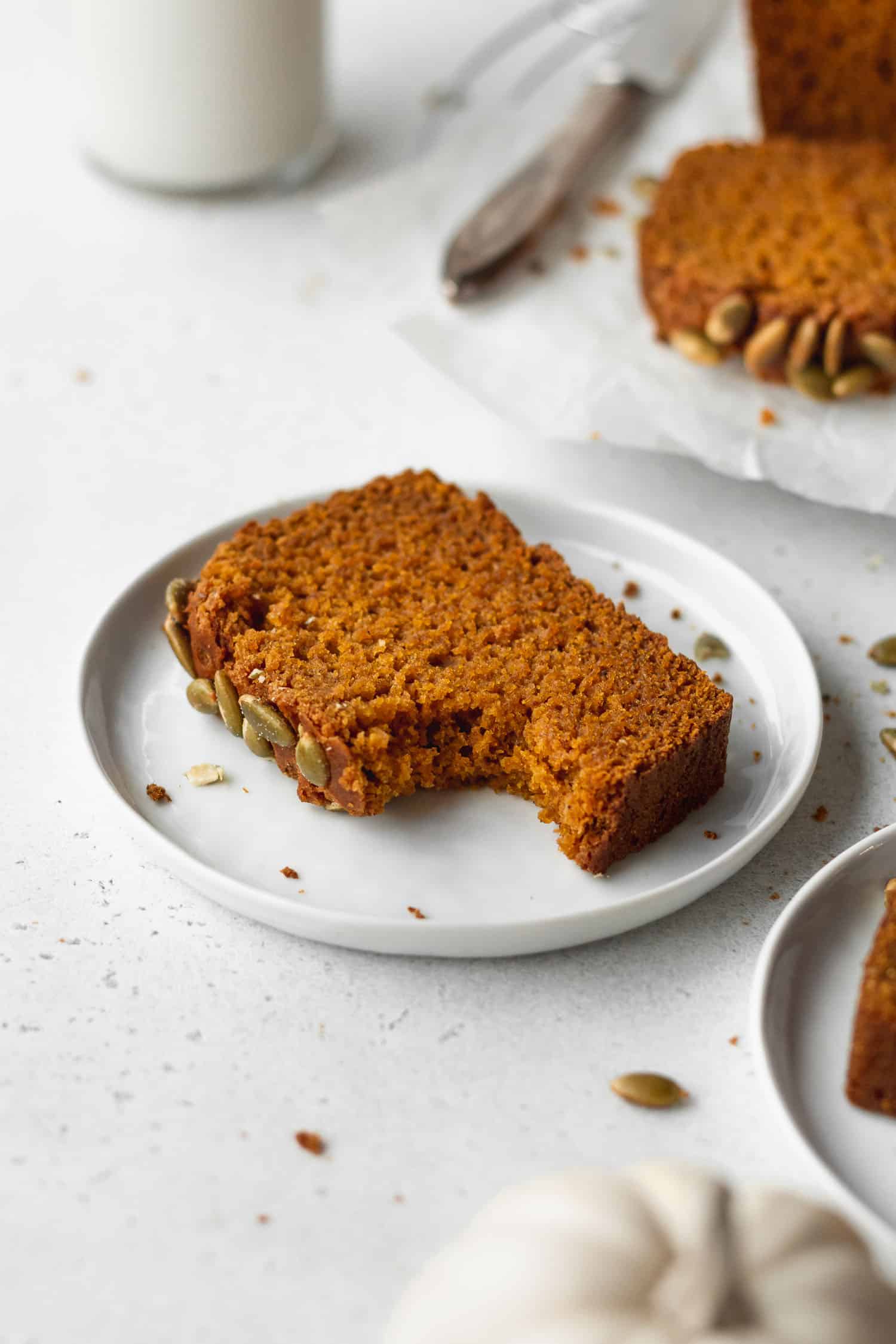 A bitten slice of gluten-free pumpkin bread on a plate.