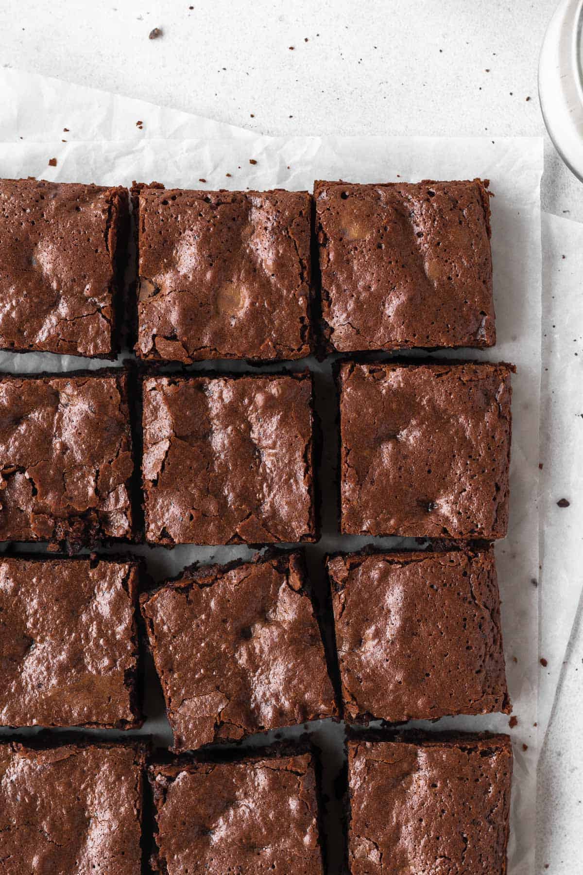 An overhead shot of a pan of sliced brownies on parchment paper.