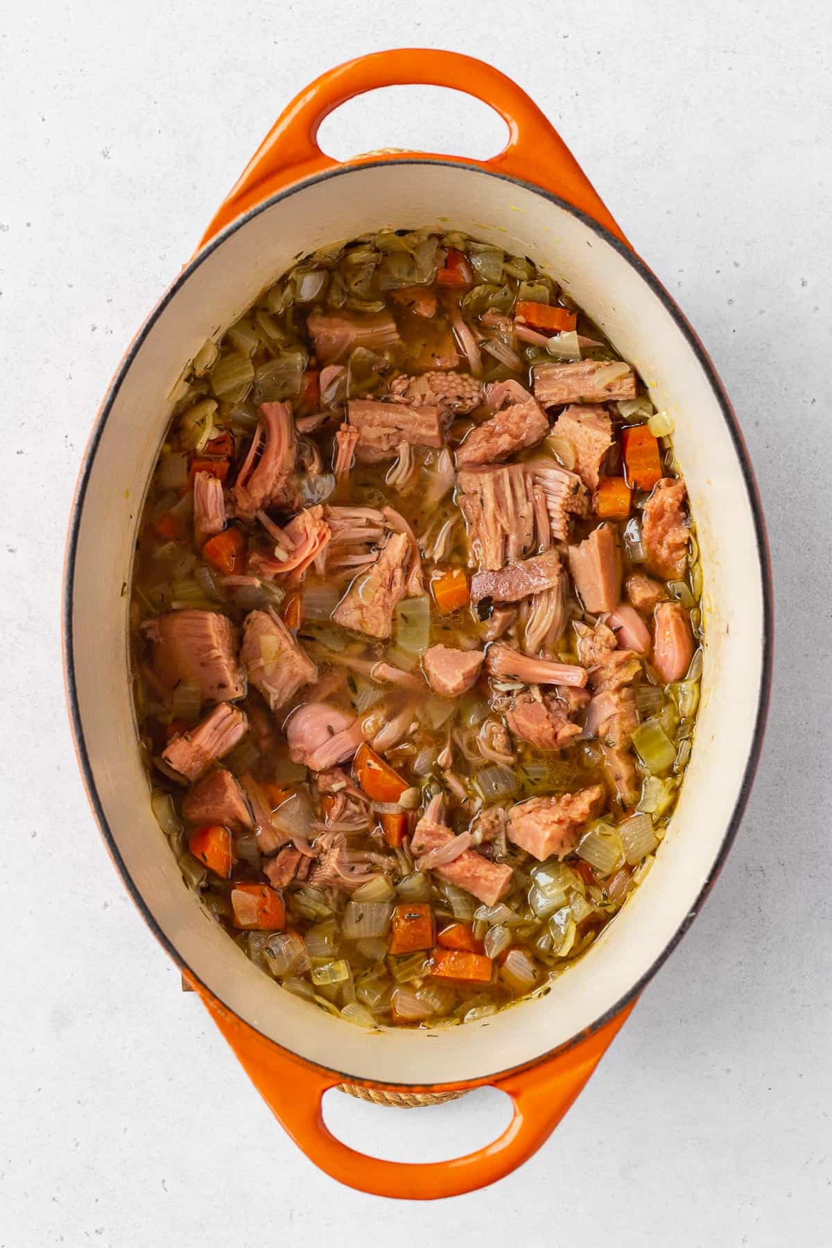 An overhead shot of a pot with vegetables, jackfruit, and vegetable stock.