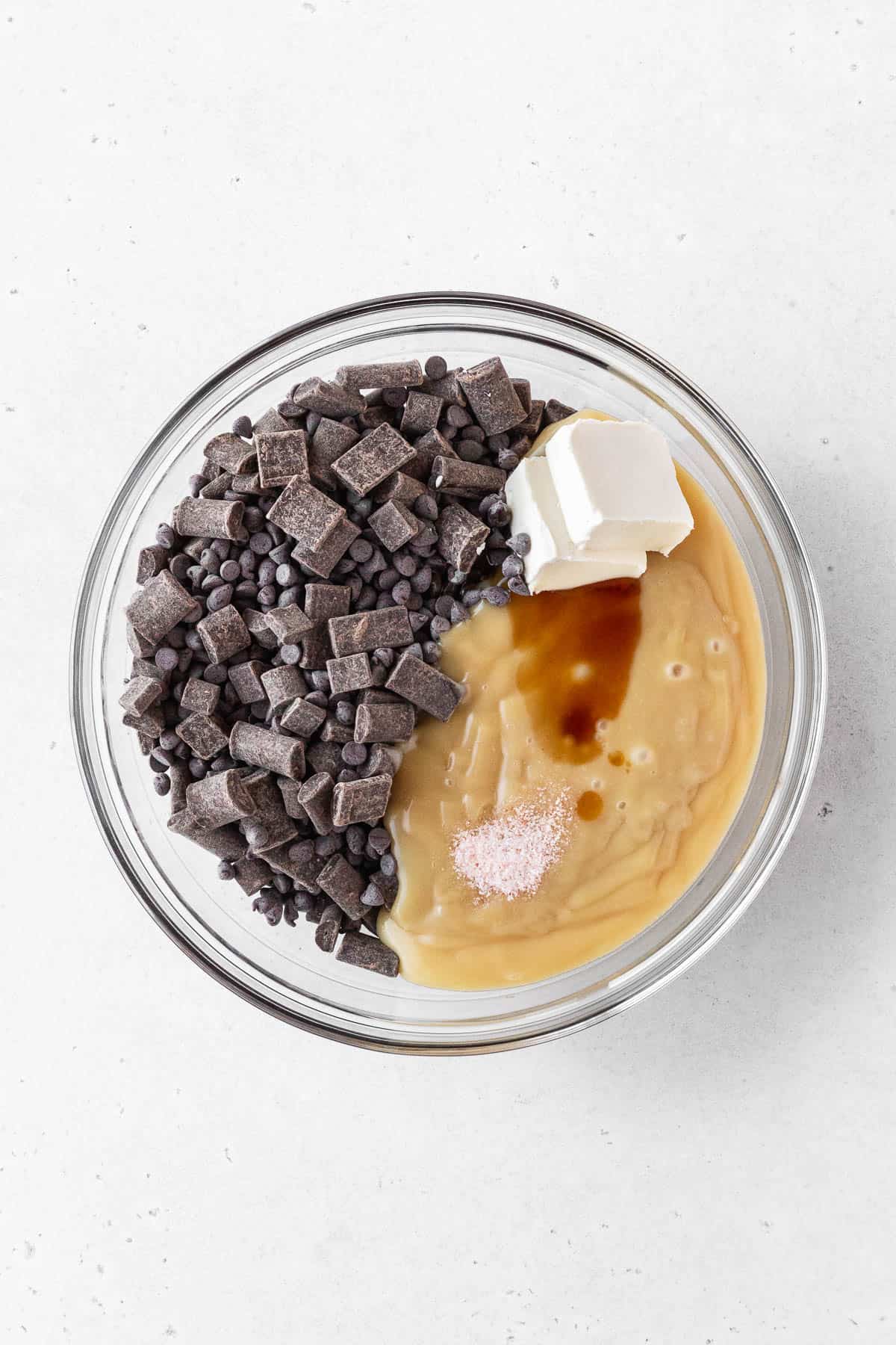 Ingredients for dairy-free fudge added to clear glass bowl.