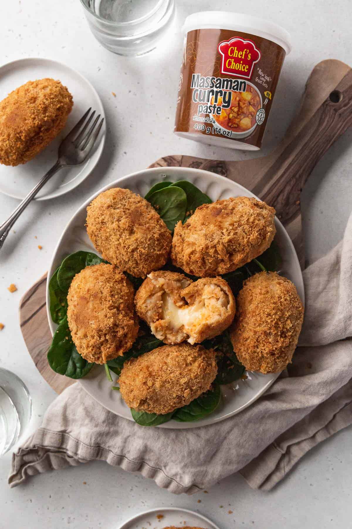 Overhead branded hero shot of vegan potato croquettes with a jar of chef's choice massaman curry paste.