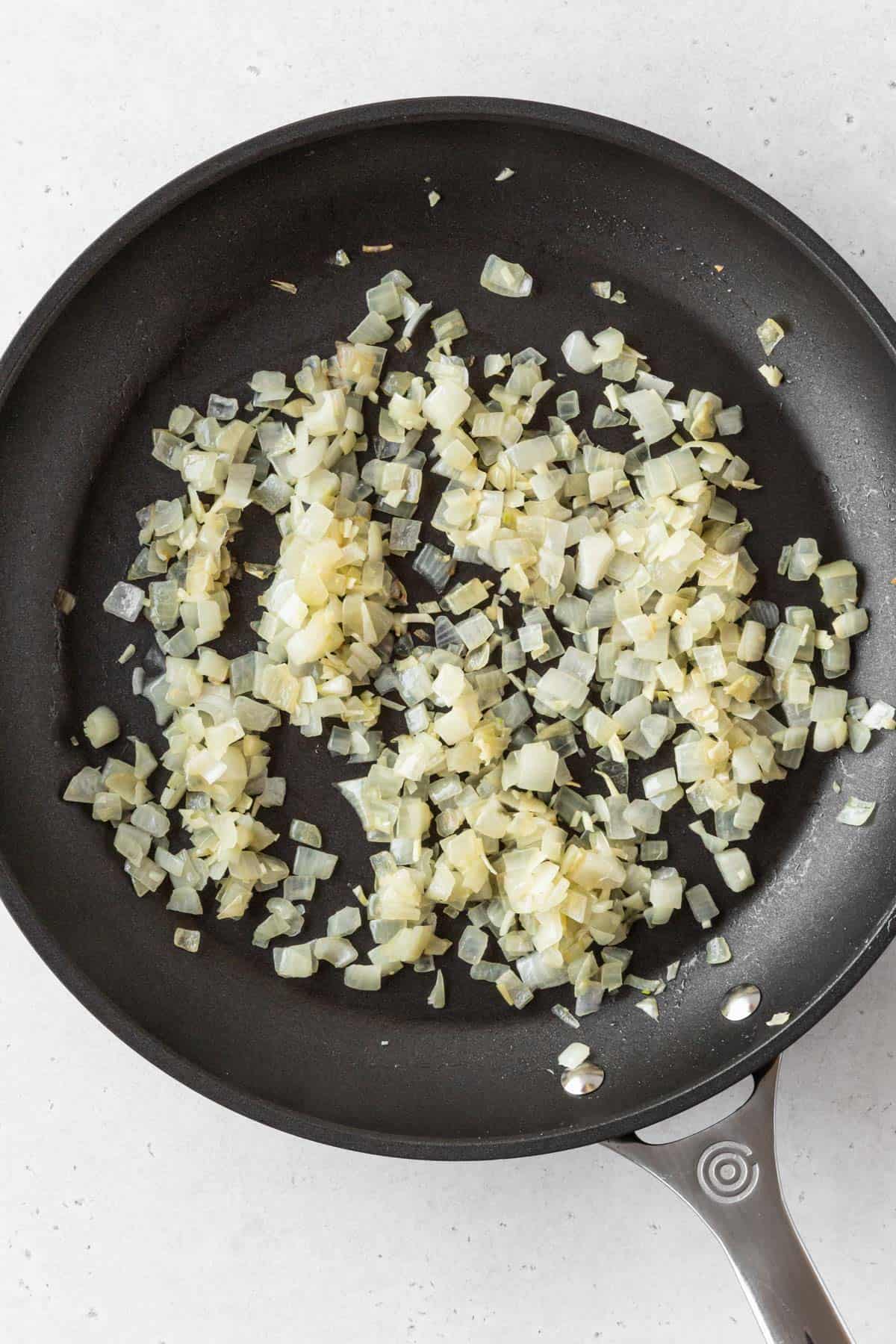 Sautéed diced onions in a pan.