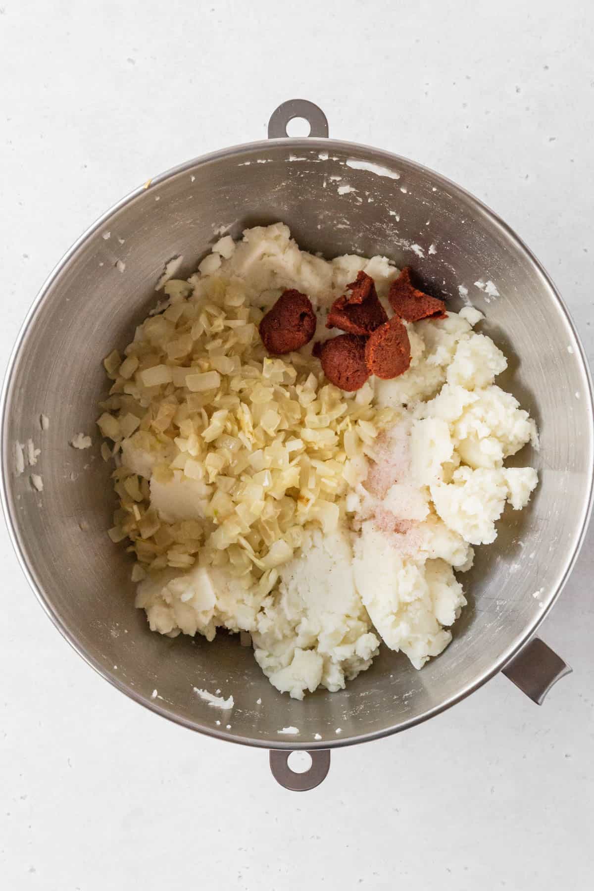Sautéed onion mix and curry paste added to bowl with mashed potato mix.