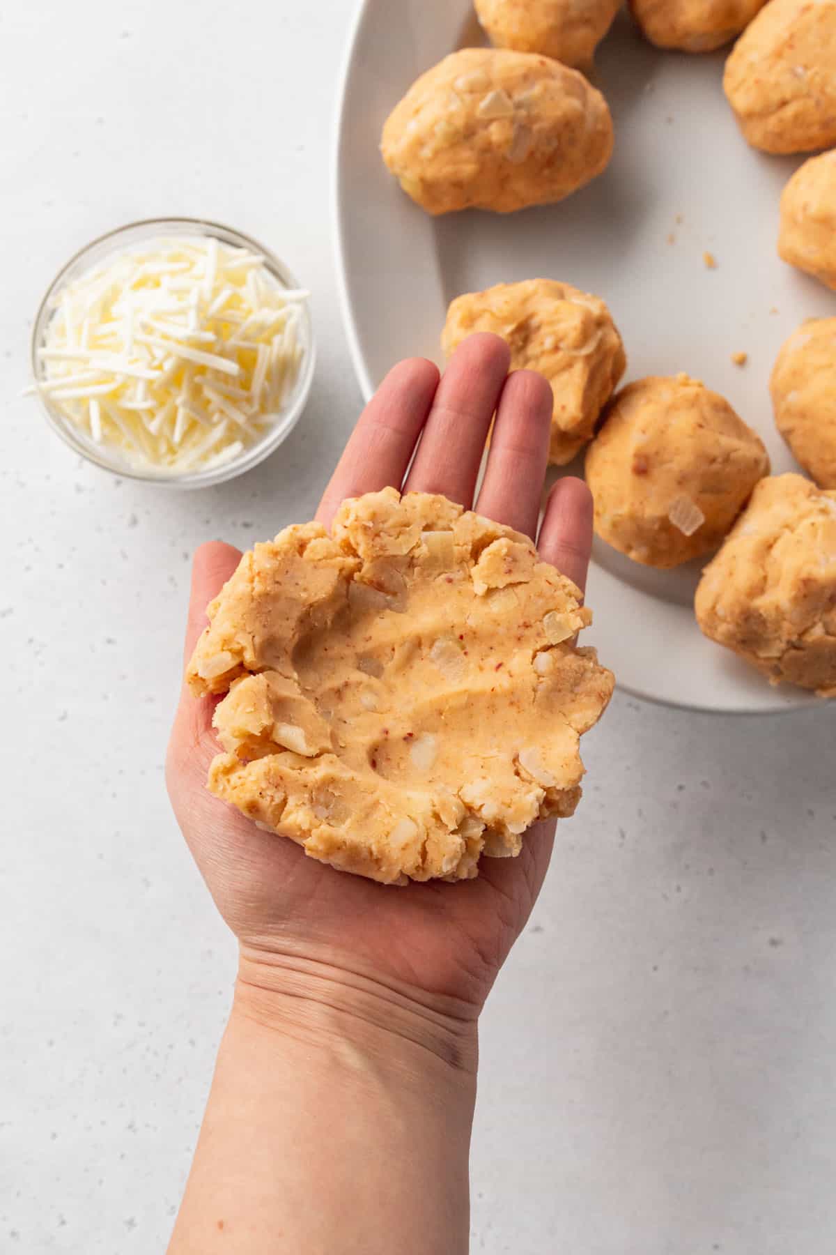 Flattened potato croquette dough is shaped like a burger patty and has thumb indents in the center for stuffing with cheese.