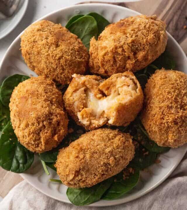 closeup on serving platter of potato croquettes with the center one broken open to reveal the gooey, cheesy center.