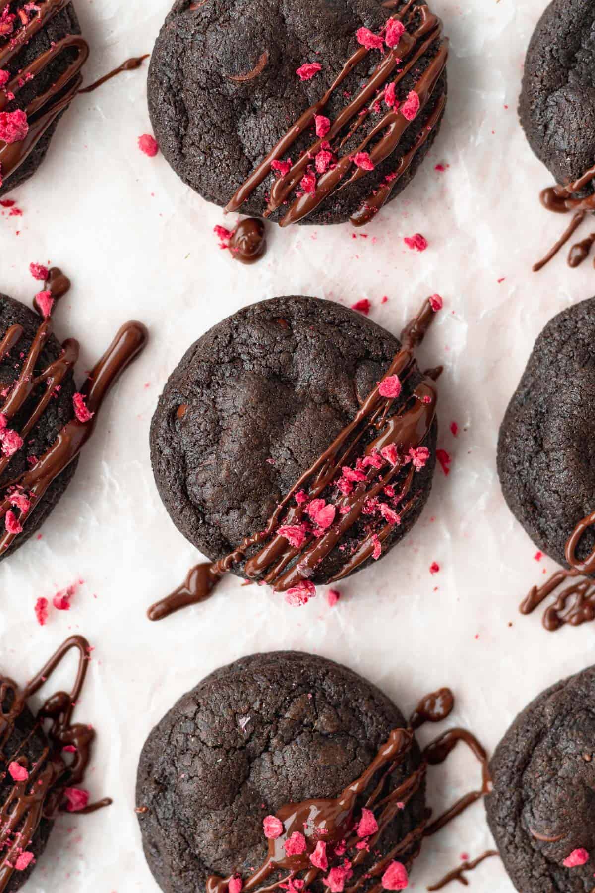 A close up shot of double chocolate chip cookies with freeze-dried raspberries sprinkled on top.