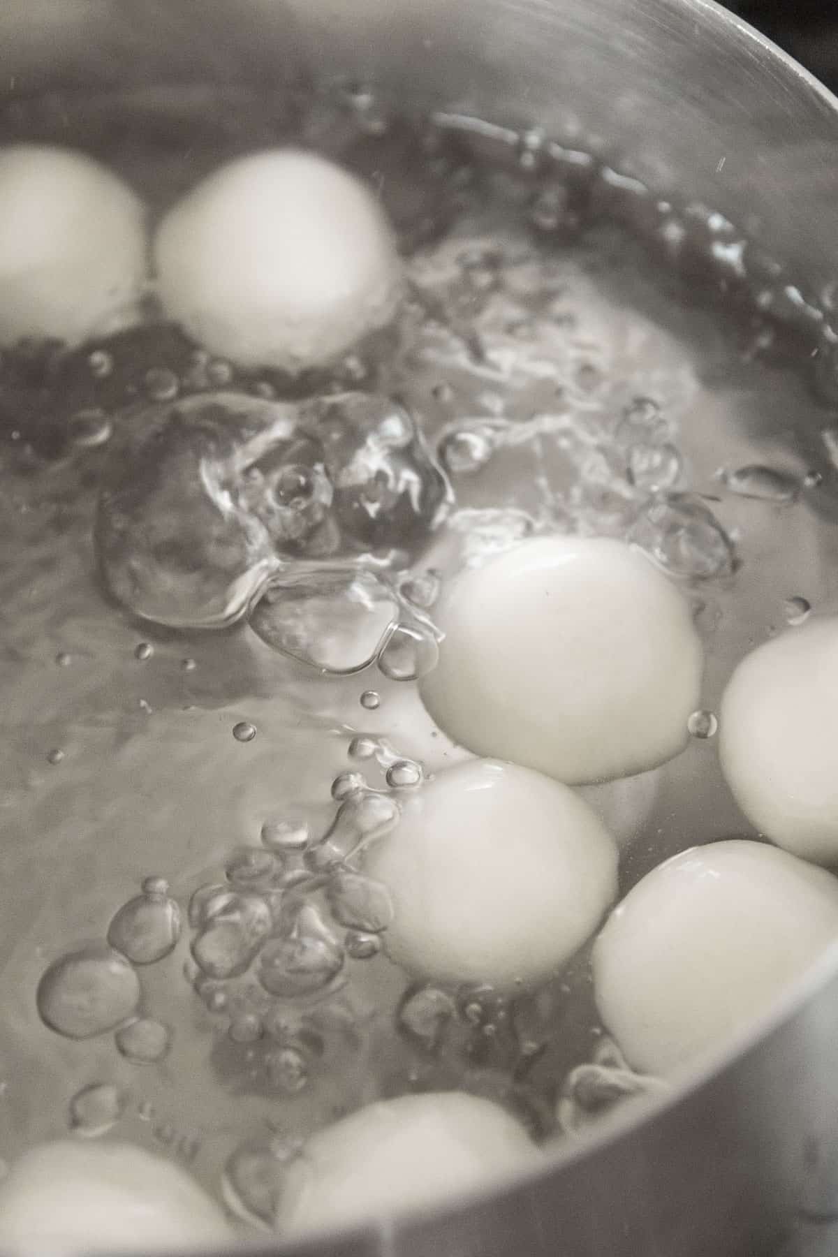 Shiratama being boiled in a silver pot of water.