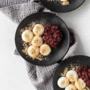 Shiratama on black plates next to some sweet red bean paste and kinako sprinkled on top.