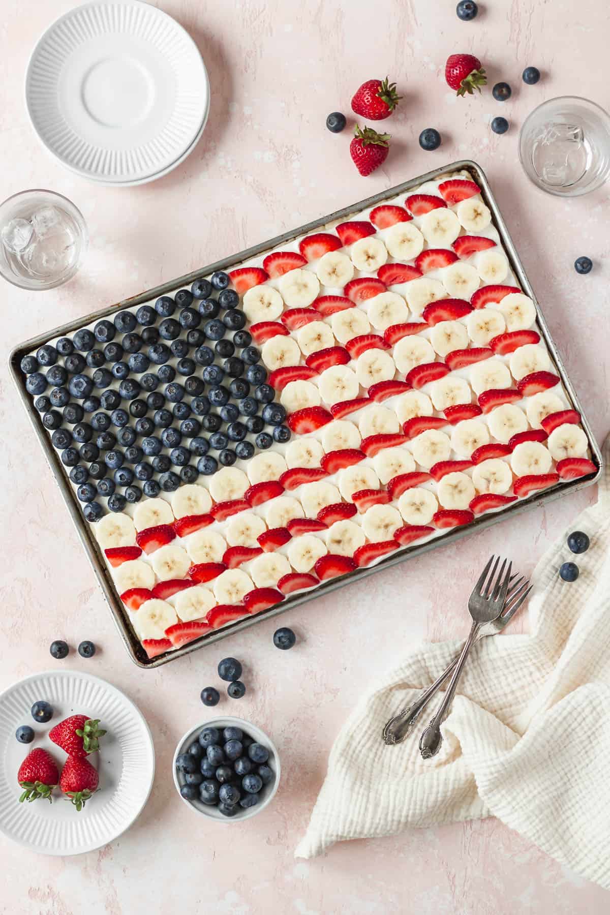 Overhead shot of the entire sheet pan of gluten free and dairy free American flag dessert pizza with blueberries, bananas, and strawberries.