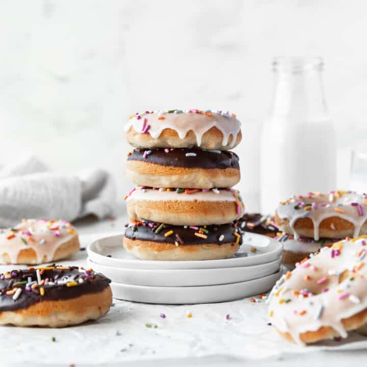 Square hero image of vanilla and chocolate glazed vegan baked donuts with colorful sprinkles.