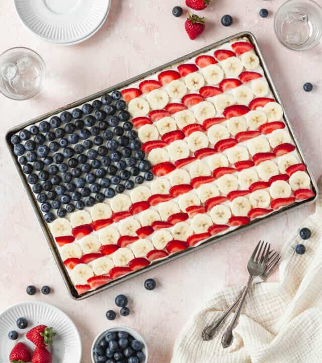 Overhead shot of the entire sheet pan of gluten free and dairy free American flag dessert pizza with blueberries, bananas, and strawberries.