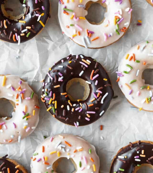 Close up shot of vanilla and chocolate glazed vegan baked donuts on a crumpled piece of parchment.