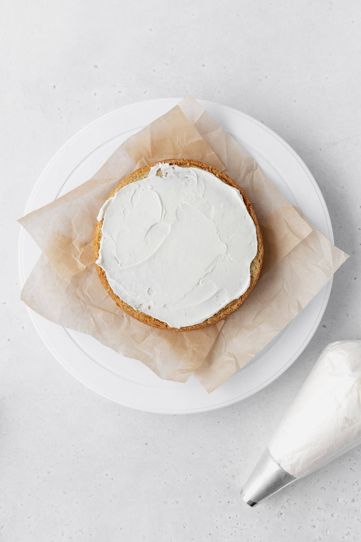 Adding a layer of buttercream on top of the first cake layer.