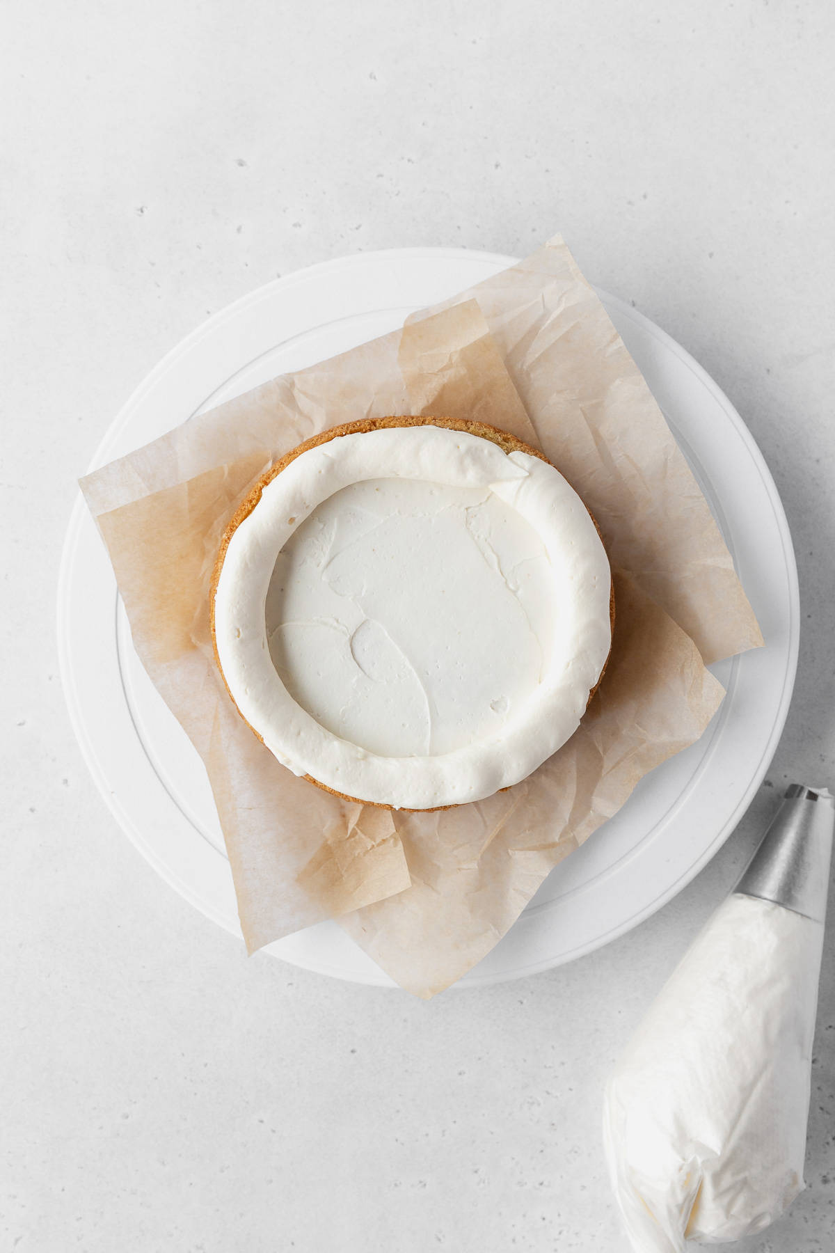 Piping a thick layer of lemon buttercream around the edge of the cake layer.