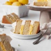 Square hero shot of a slice of dairy-free lemon curd cake on a white dessert plate.