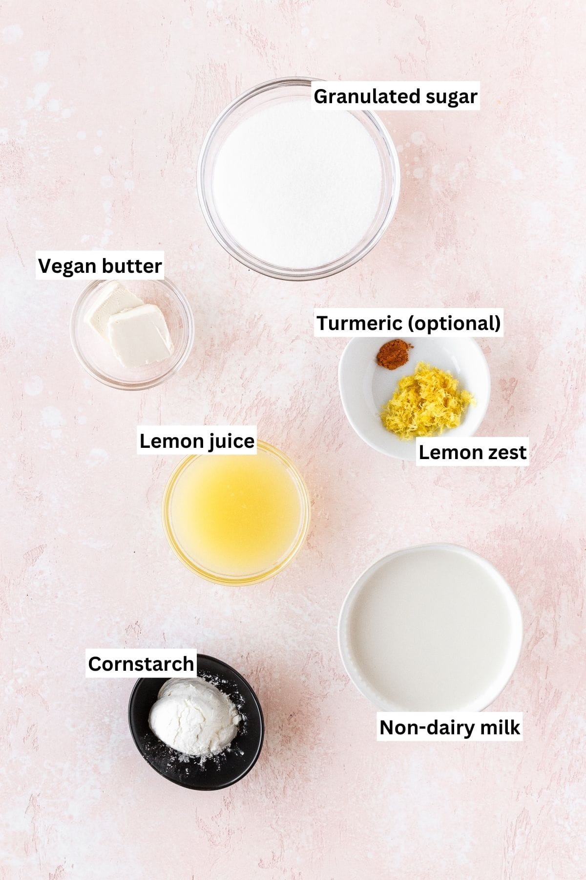 Ingredients needed for making vegan lemon curd measured out into bowls on a pink table with text overlay.