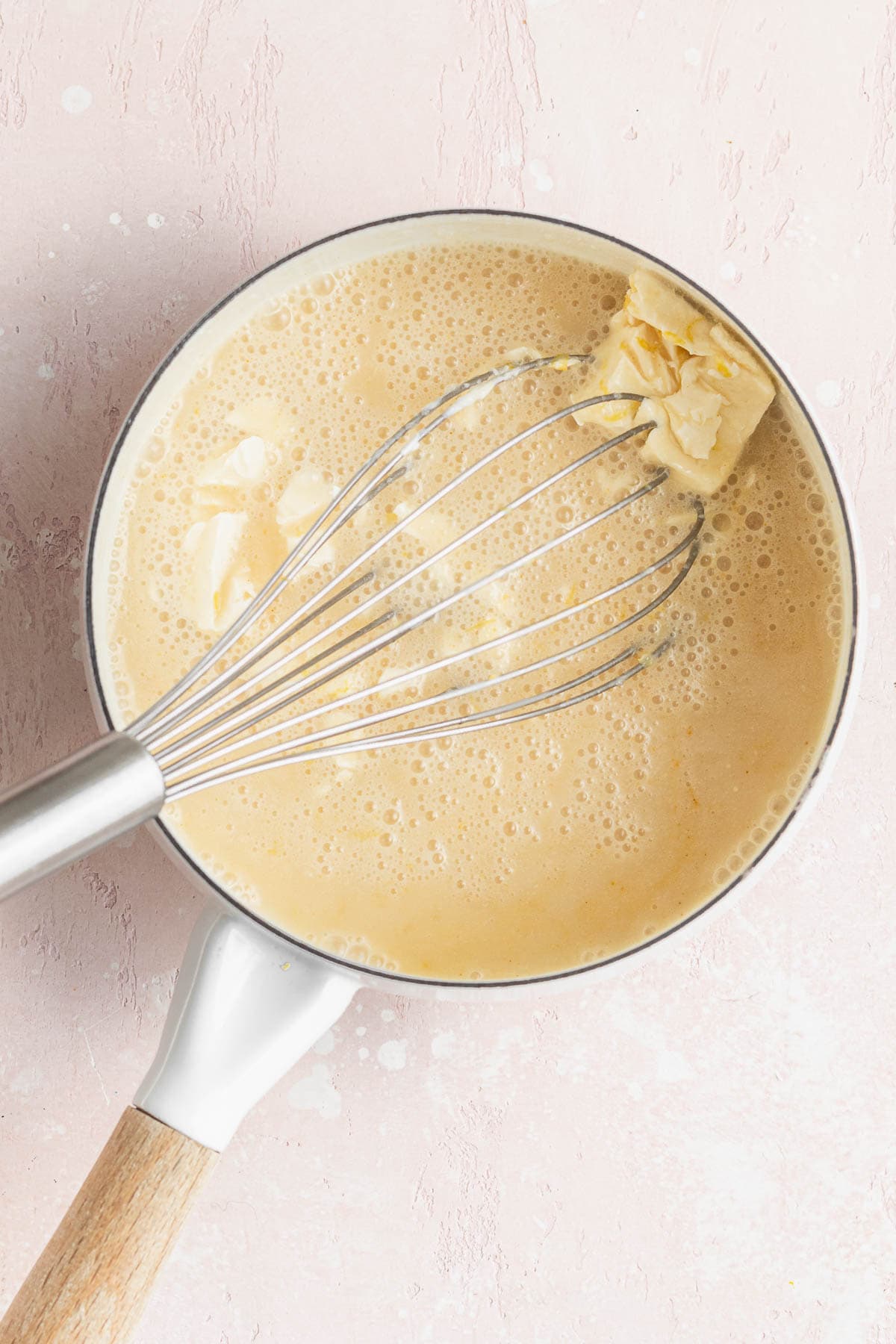 Whisking the butter into the warmed vegan lemon curd mixture in a saucepan.