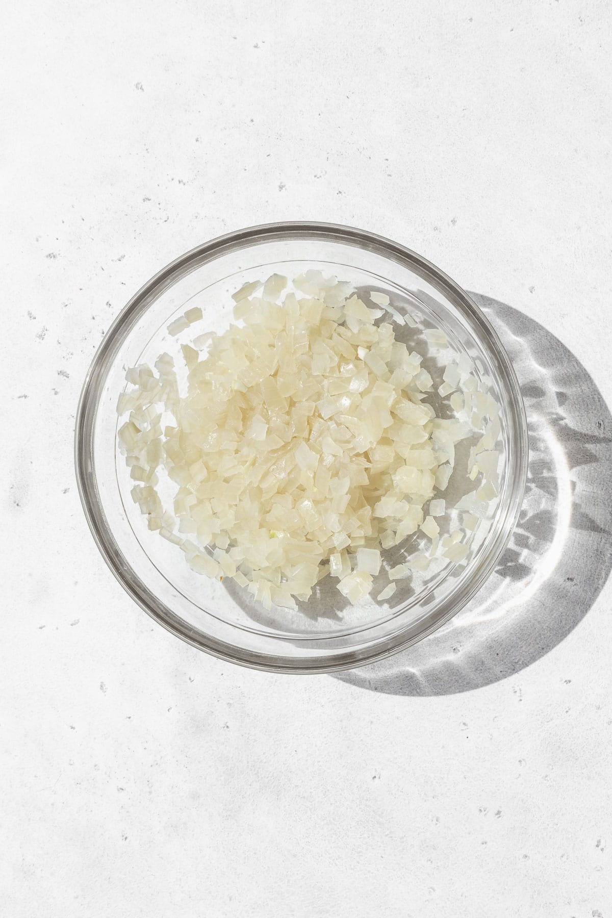 Microwaved minced onion in a glass bowl.