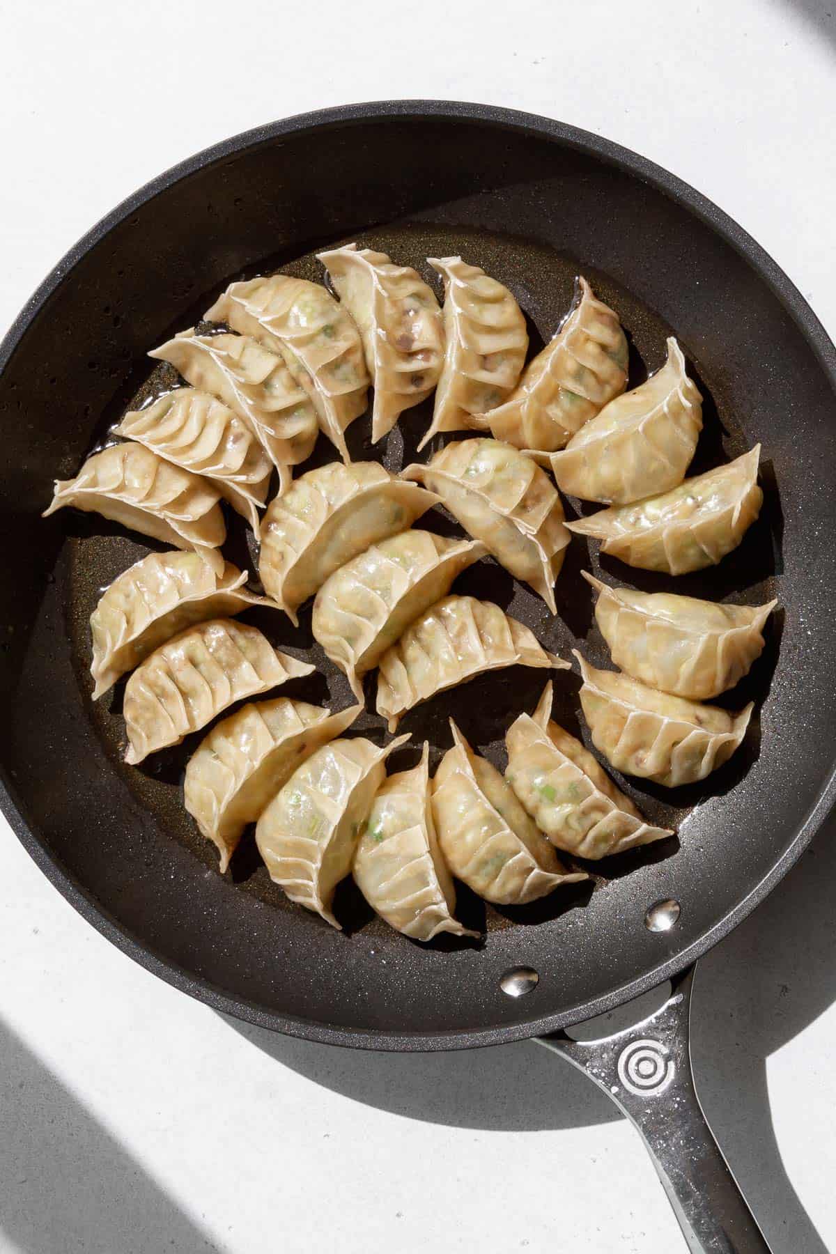 Cooked vegan gyoza on a frying pan.