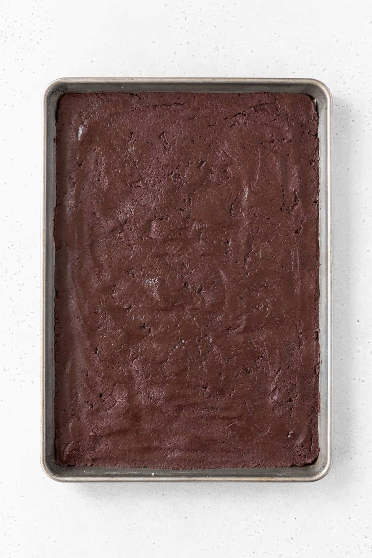 Chocolate sandwich cookie batter spread out on a baking sheet.