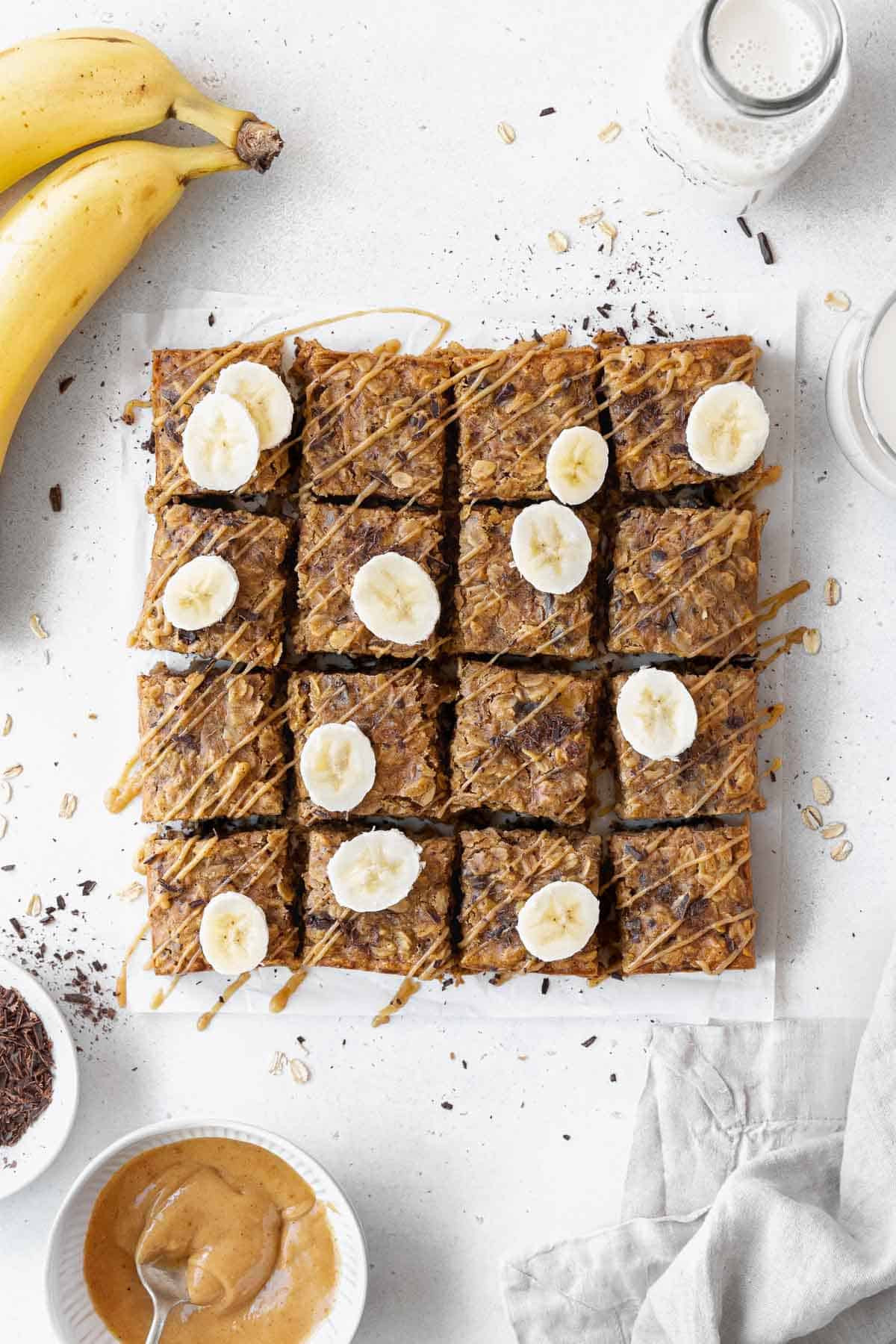 And overhead shot of pan of sliced peanut butter banana oatmeal bars on a piece of parchment paper.