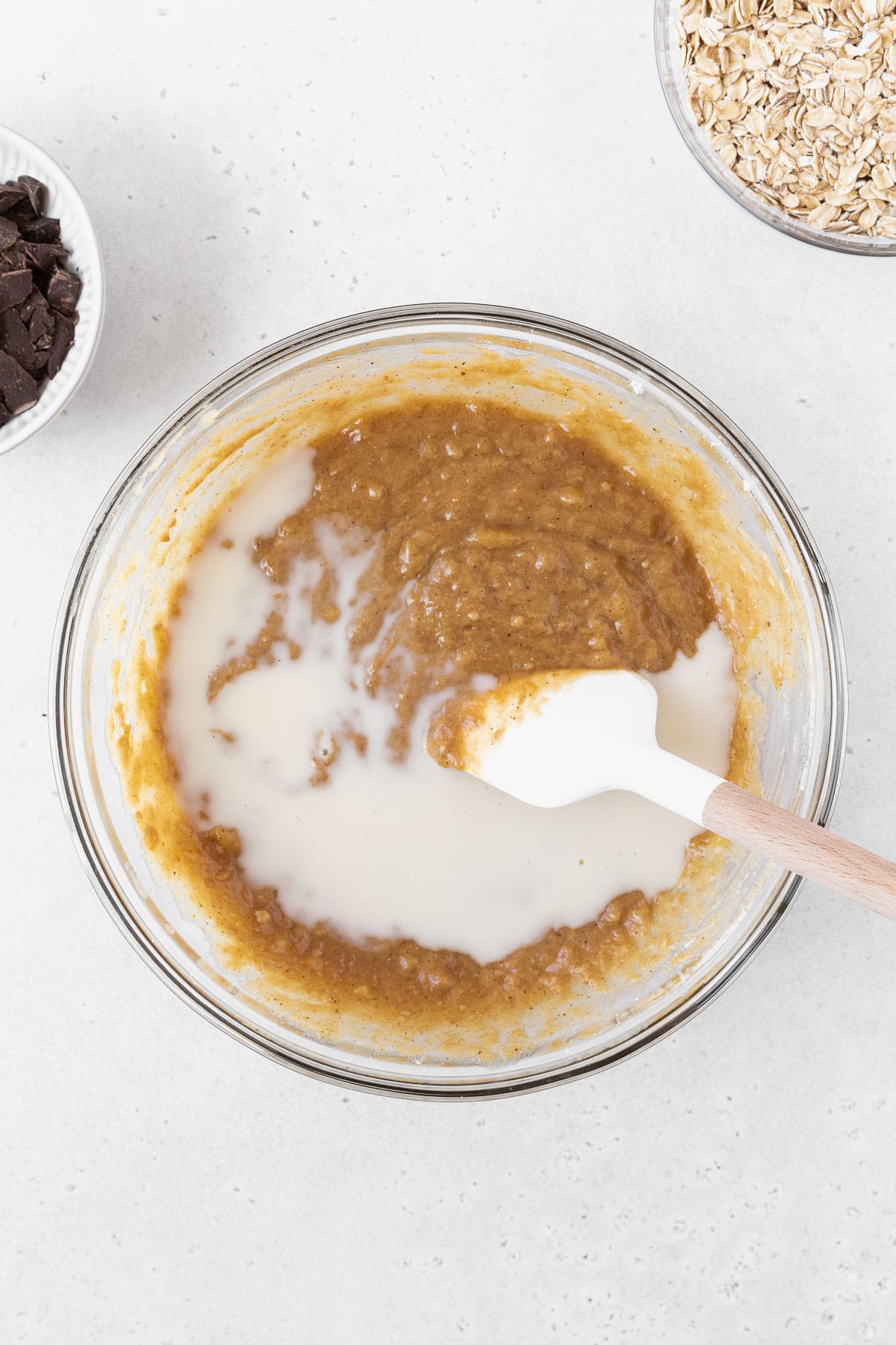 Stirring the milk into the bowl of peanut butter and banana bars batter.