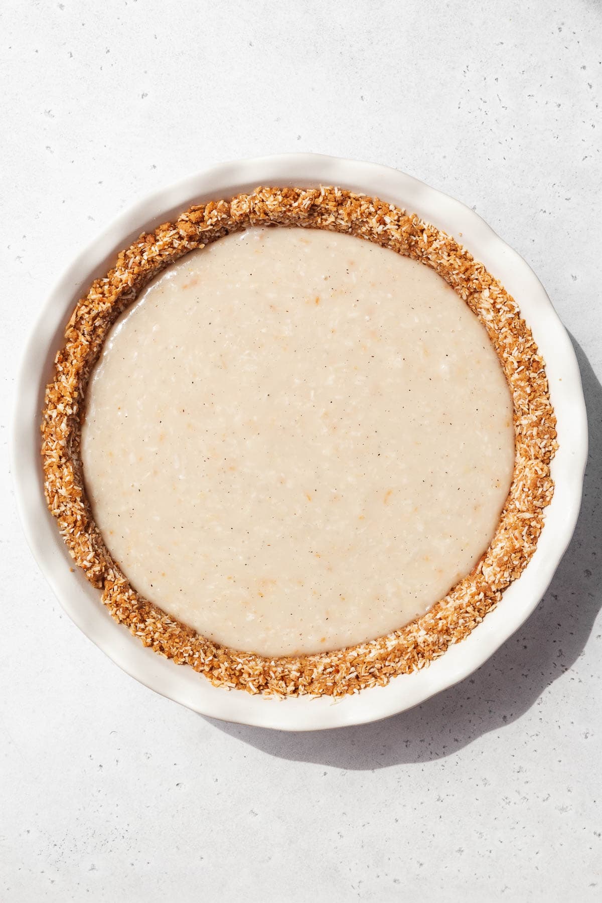 Vegan coconut custard poured into the chilled gluten-free pie crust.