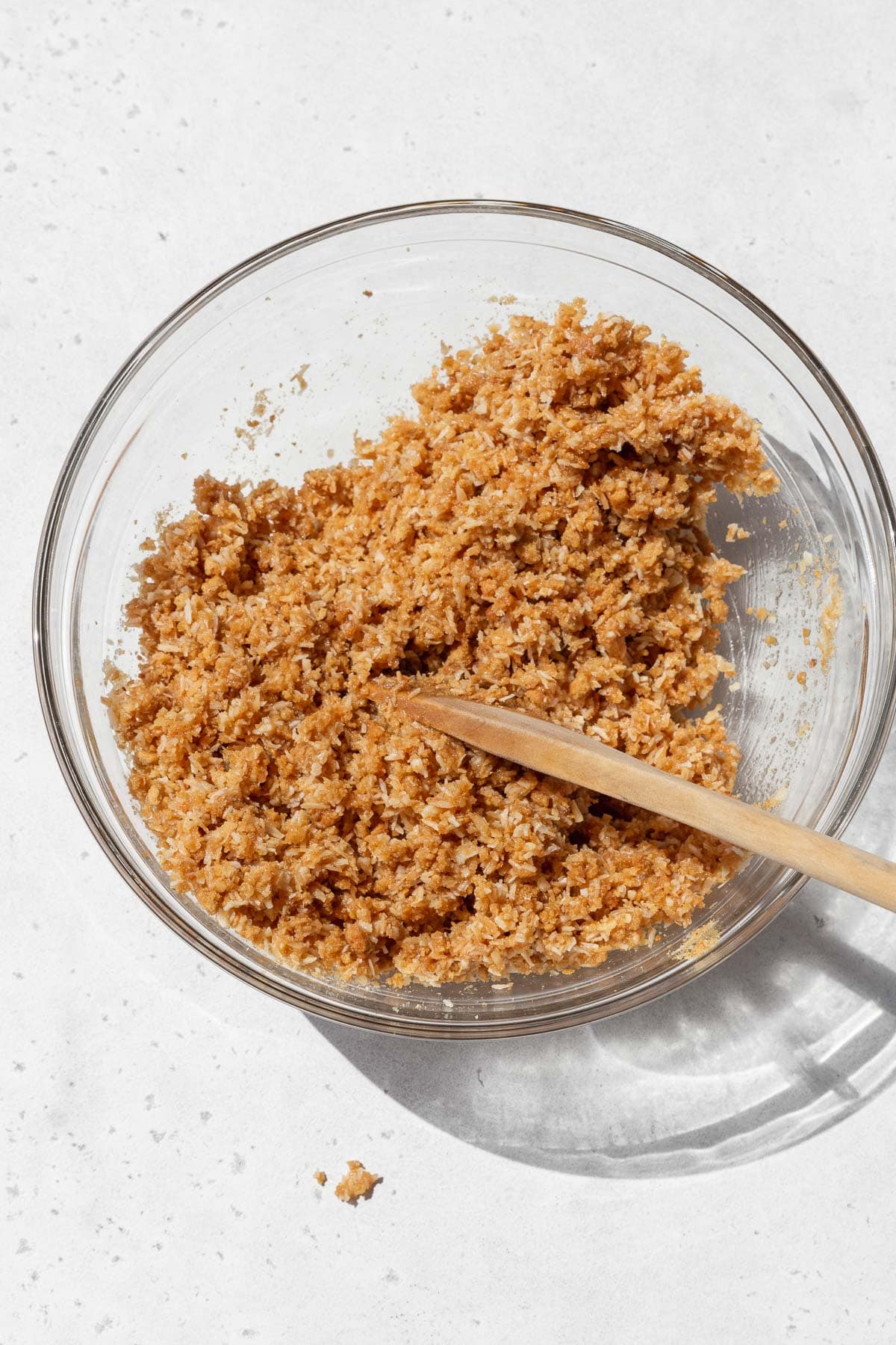 Gluten-free coconut pie crust mixture in a bowl after adding the vegan butter. It looks like wet sand.