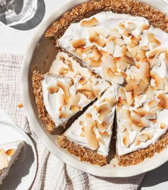 overhead shot of vegan gluten-free coconut cream pie in a pie dish with two slices prepped to serve.