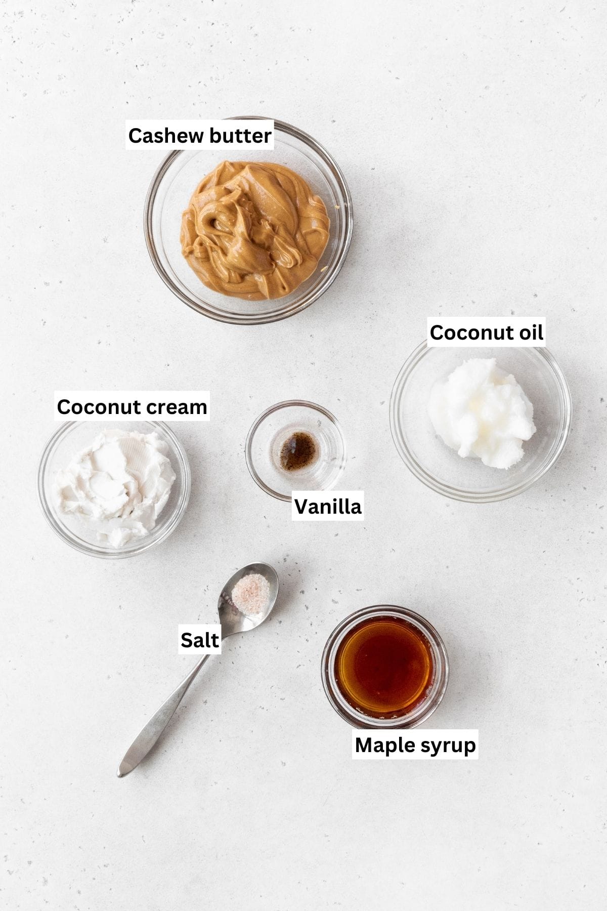 Overhead shot of maple cashew frosting ingredients on a white surface.