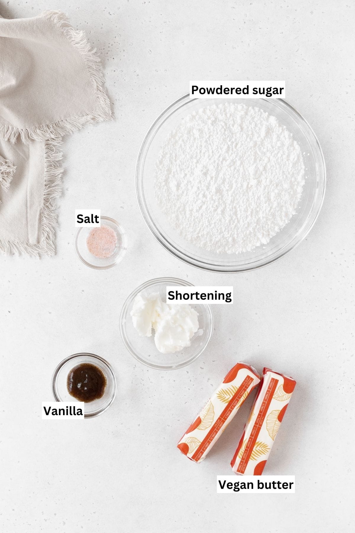 Ingredients needed to make dairy-free buttercream frosting laid out on a white table with text overlay.