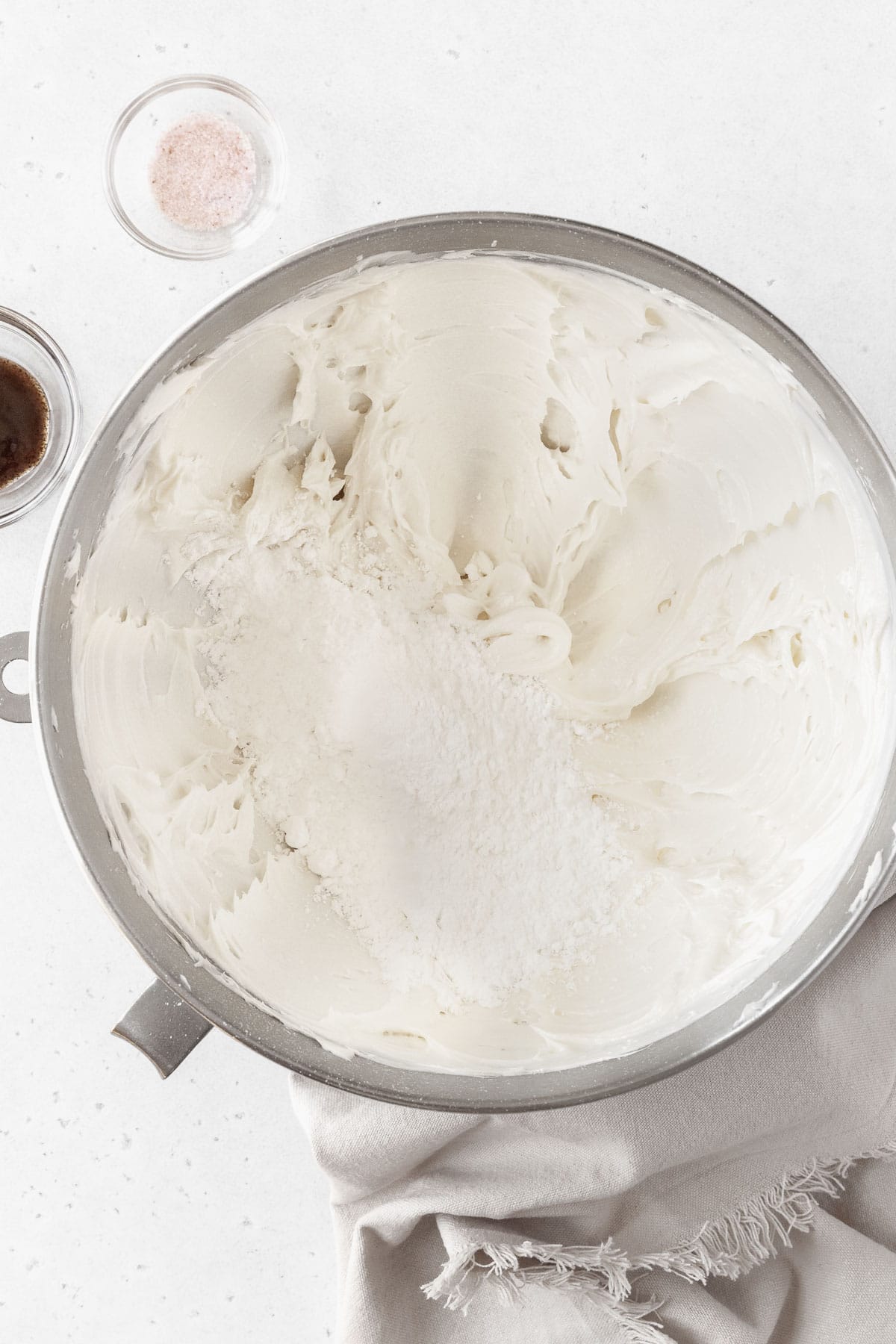 Powdered sugar being added to the large bowl of whipped butter.