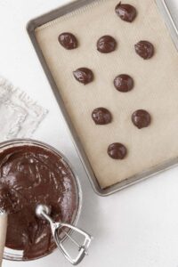 Scooping the gluten-free whoopie pie batter onto a parchment paper lined baking sheet.
