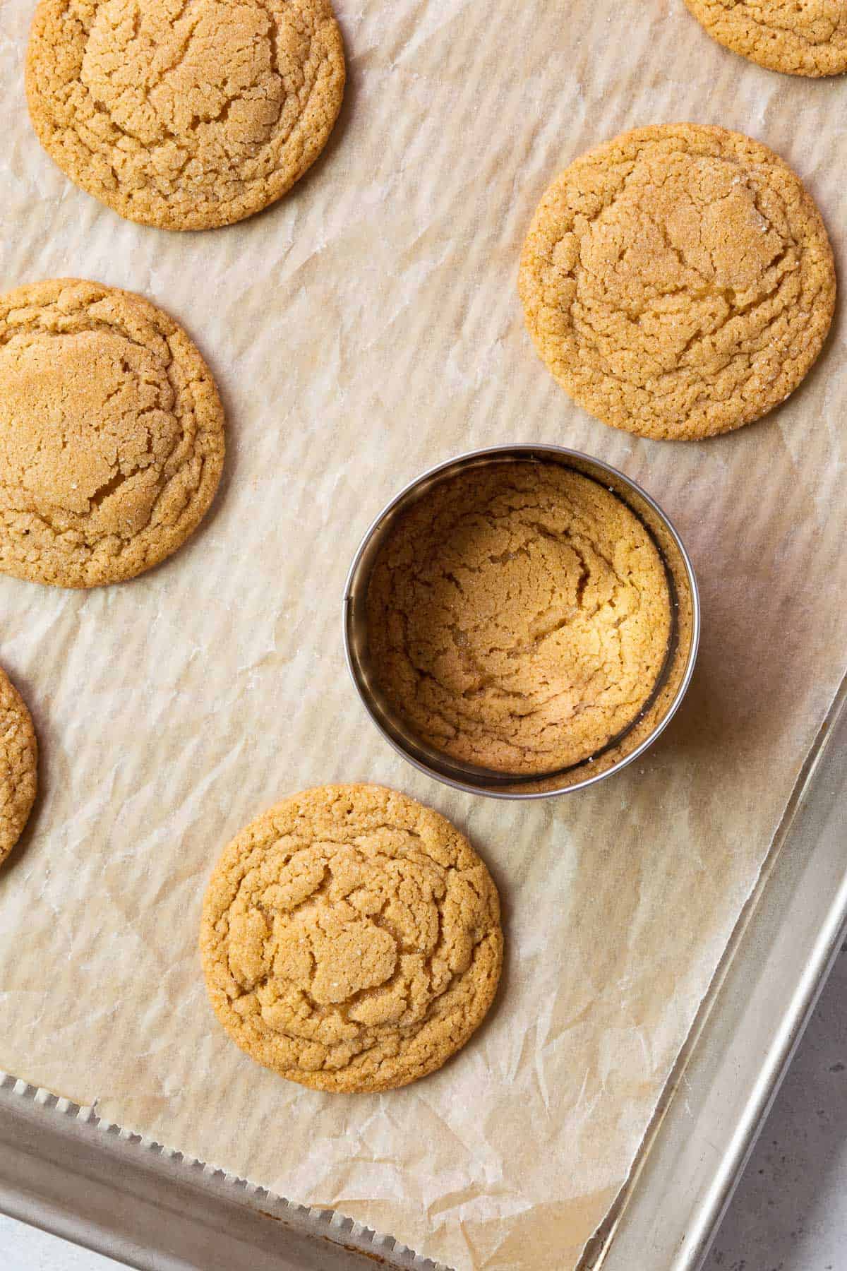 Shaping the peanut butter cookie with a cookie cutter on a parchment paper-lined baking sheet.