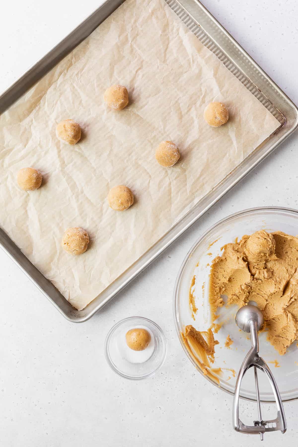 Scooping and rolling out the dairy free peanut butter cookies onto the prepared baking tray.