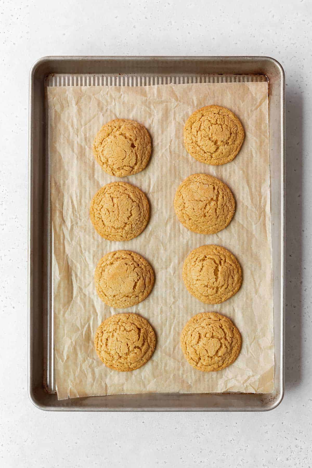 Baked dairy-free peanut butter cookies on a parchment paper-lined baking sheet.
